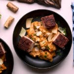 pumpkin spice pork belly with a pumpkin spice cream sauce on a black bowls on a white surface