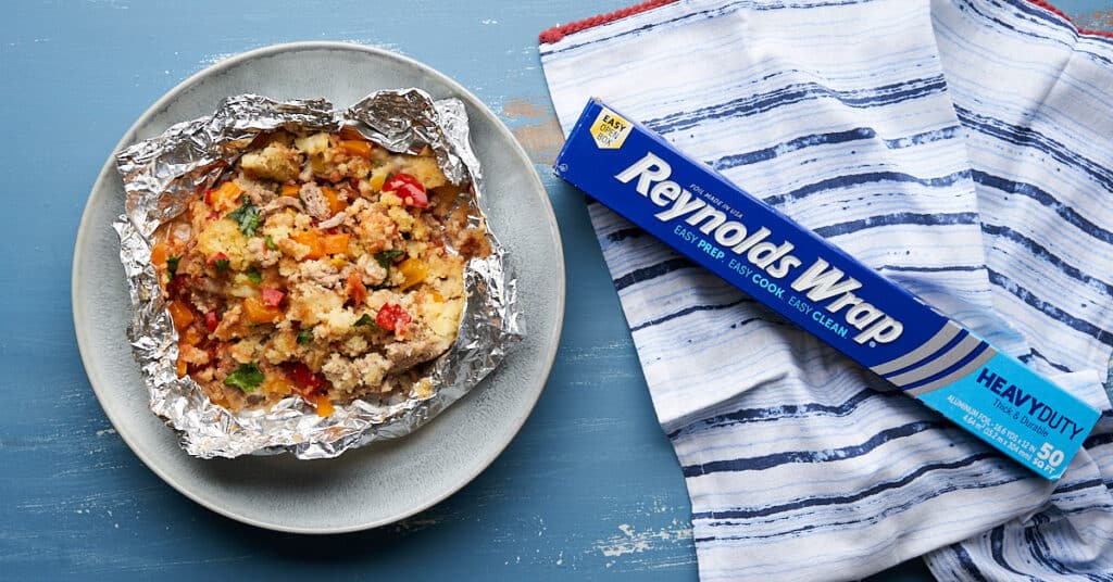 Turkey Tamale Pie On foil and a plate laying on a blue surface with a roll of foil next to it