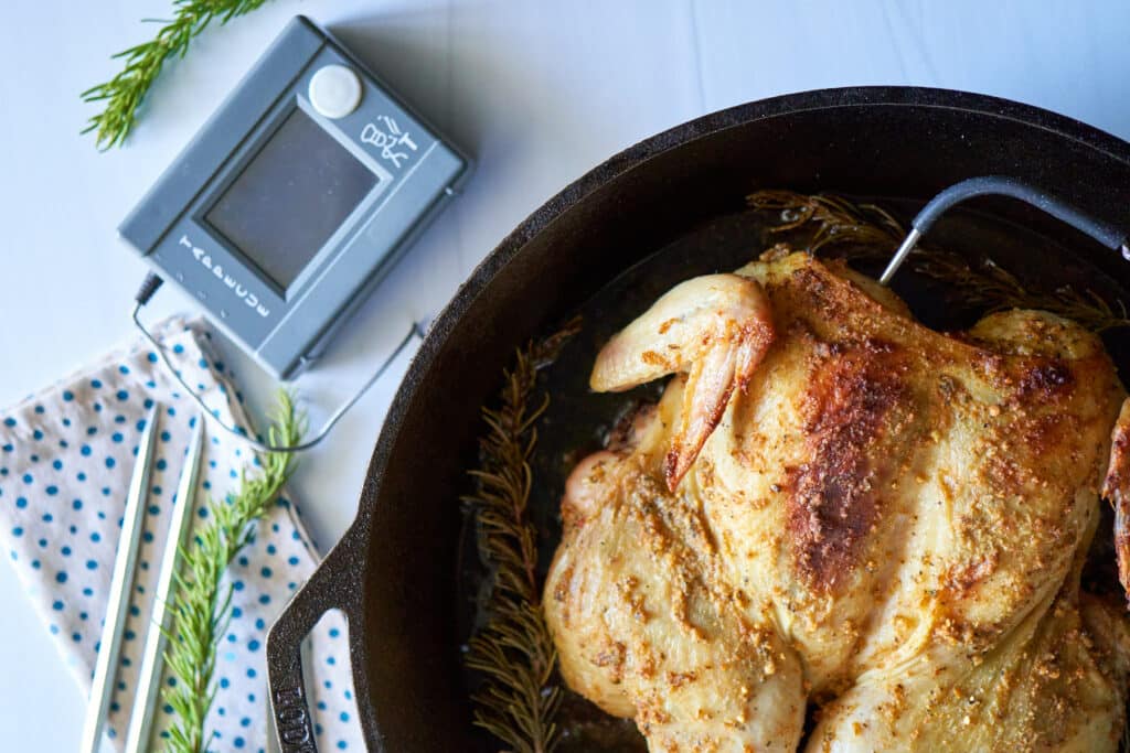 A cast iron roasted whole chicken and a Tappecue Wireless Thermometer