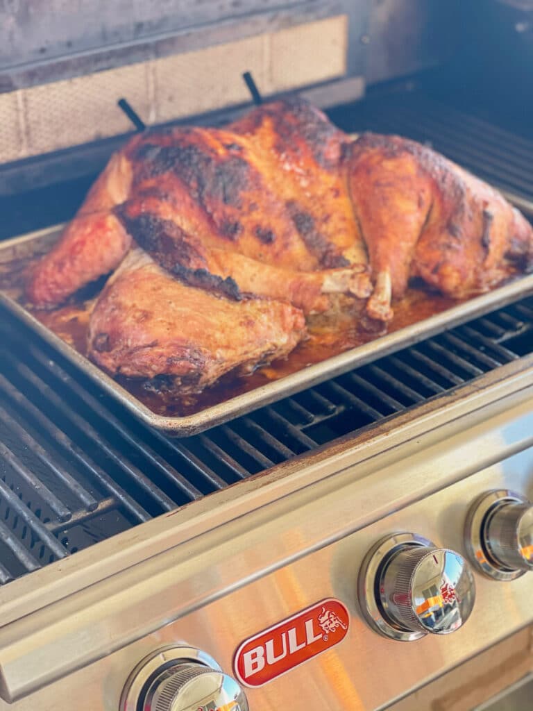 a turkey spatchcocked cooking on a grill